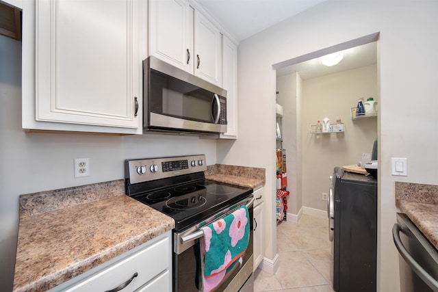 kitchen featuring white cabinets, light countertops, light tile patterned floors, baseboards, and appliances with stainless steel finishes