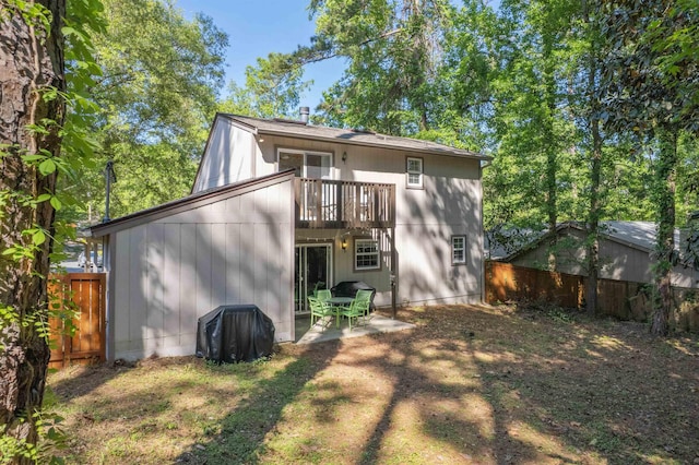 rear view of property featuring a fenced backyard, a patio area, and a balcony