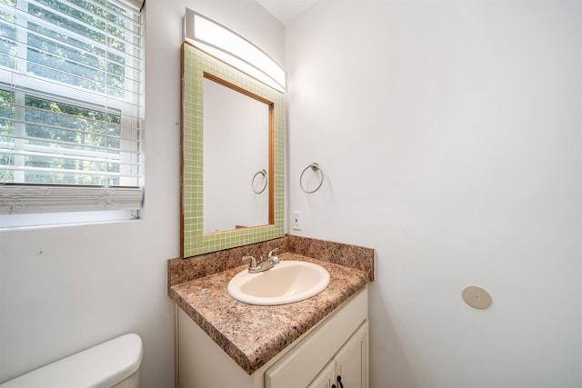 bathroom featuring a wealth of natural light, toilet, and vanity