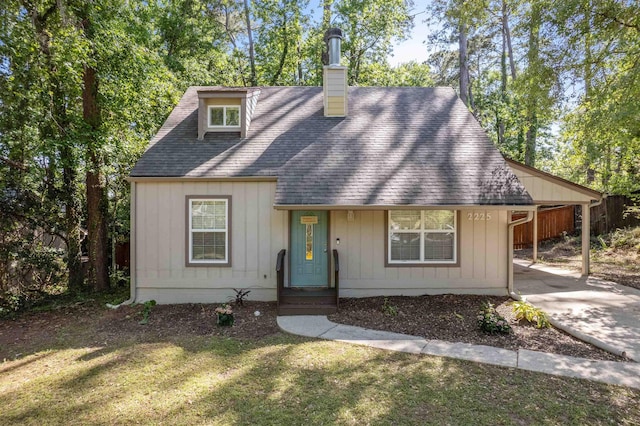 view of front of home with a chimney, a front lawn, driveway, an attached carport, and roof with shingles