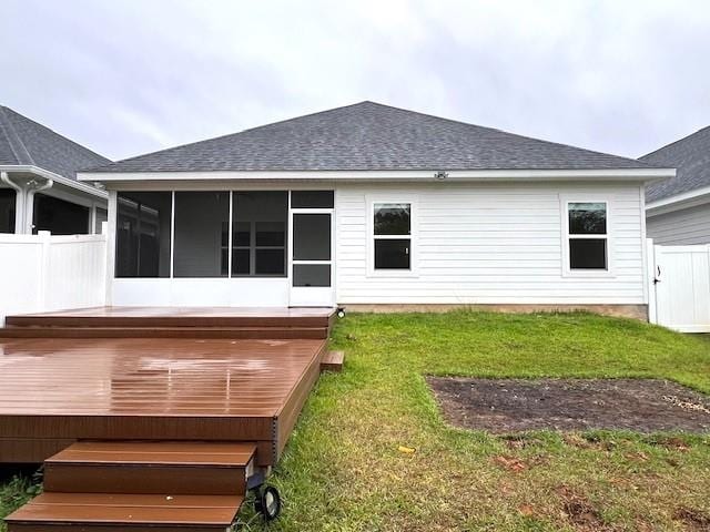 back of property with a yard, a sunroom, and a deck