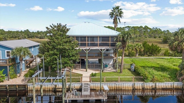 back of house with a patio, a water view, and a lawn