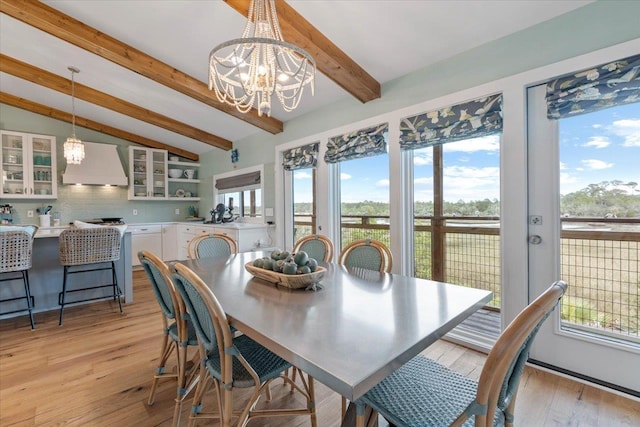 dining area featuring a notable chandelier, vaulted ceiling with beams, light hardwood / wood-style floors, and plenty of natural light