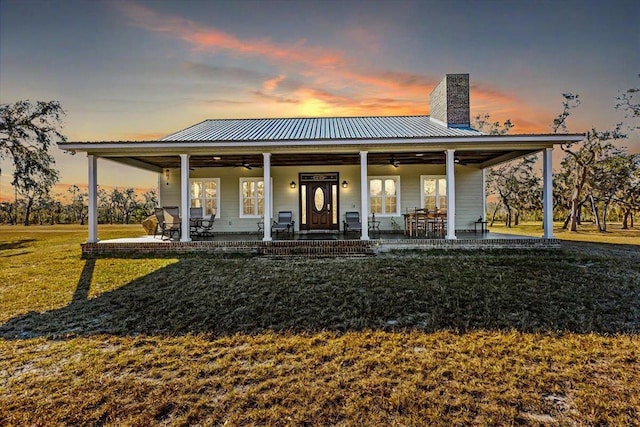 back house at dusk with a patio, a yard, and ceiling fan