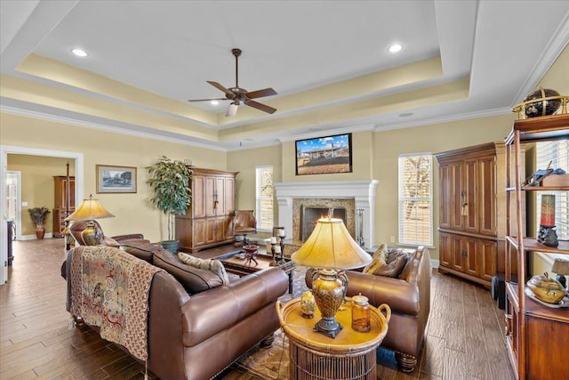 living room featuring crown molding, a tray ceiling, a fireplace, and dark hardwood / wood-style floors