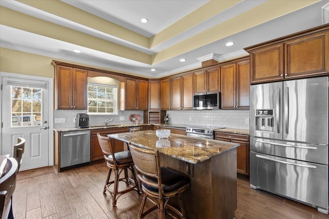 kitchen featuring a kitchen island, dark hardwood / wood-style flooring, a kitchen breakfast bar, dark stone counters, and stainless steel appliances