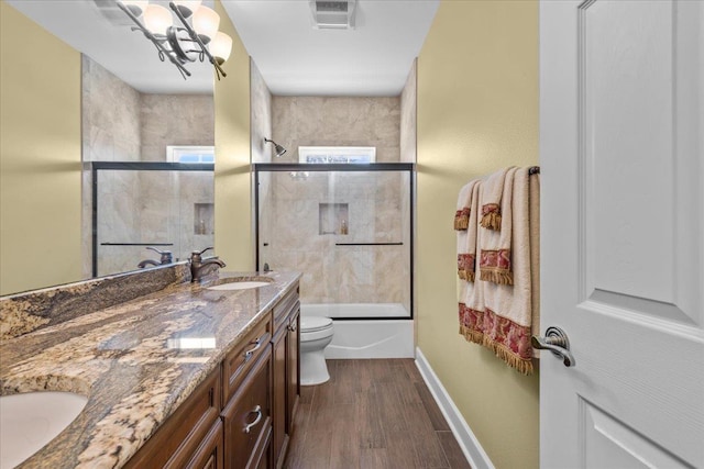 full bathroom with shower / bath combination with glass door, a chandelier, vanity, wood-type flooring, and toilet