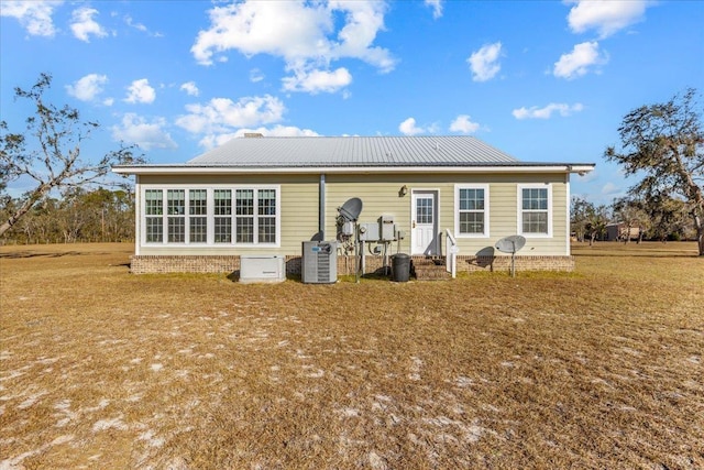 rear view of house with central AC unit and a lawn