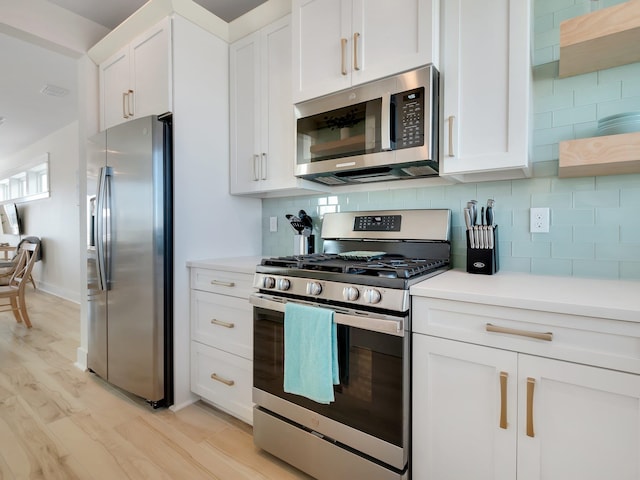 kitchen featuring tasteful backsplash, light wood-type flooring, white cabinets, and stainless steel appliances