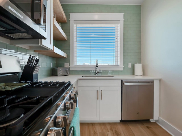 kitchen with white cabinetry, stainless steel appliances, sink, and light hardwood / wood-style flooring