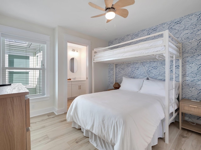 bedroom featuring light hardwood / wood-style floors, ceiling fan, ensuite bath, and sink