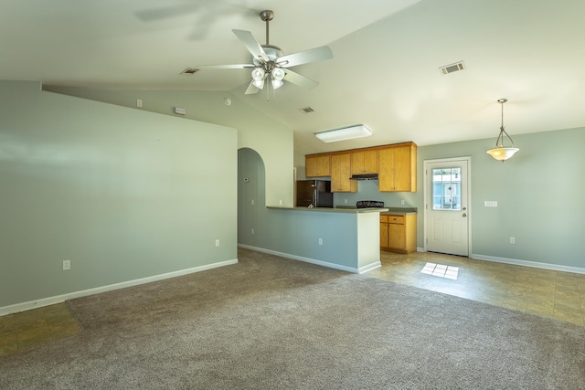 kitchen featuring vaulted ceiling, black refrigerator, carpet flooring, hanging light fixtures, and kitchen peninsula