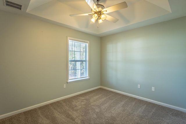 carpeted empty room with a tray ceiling and ceiling fan