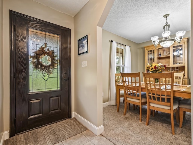 tiled entrance foyer with an inviting chandelier and a textured ceiling