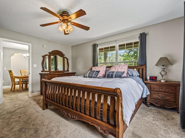 bedroom with ceiling fan, light colored carpet, and a textured ceiling