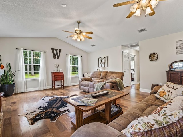 living room featuring washer / clothes dryer, vaulted ceiling, a textured ceiling, and light wood-type flooring