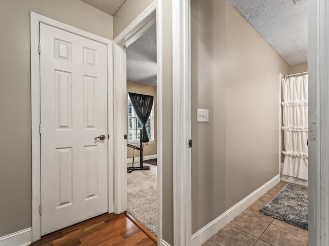 hall featuring tile patterned flooring and a textured ceiling