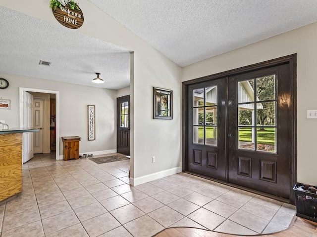 tiled foyer featuring french doors and a textured ceiling