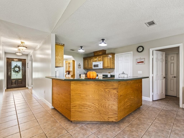 kitchen featuring light tile patterned floors, kitchen peninsula, and a textured ceiling