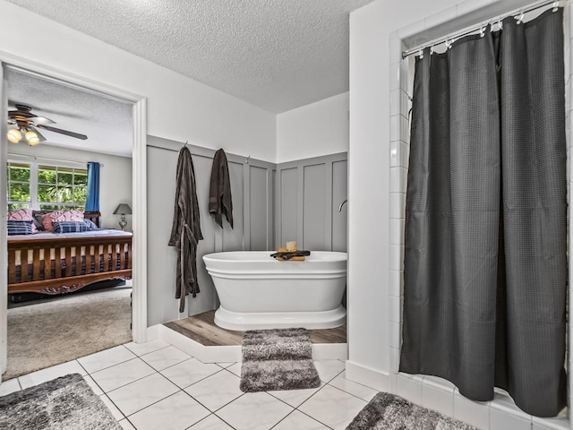 bathroom with tile patterned flooring, ceiling fan, a tub, and a textured ceiling