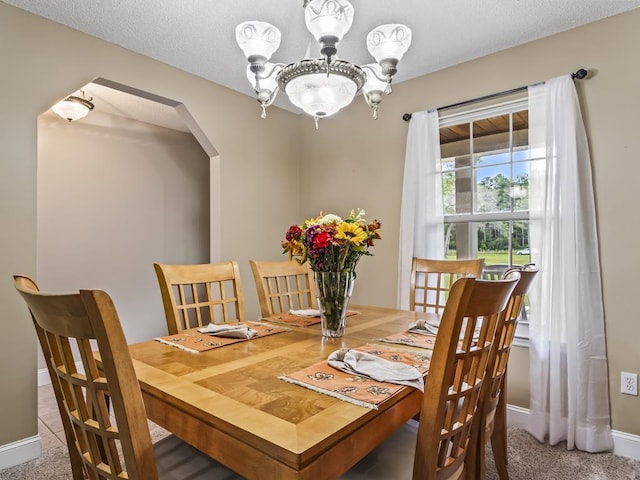 carpeted dining space with a notable chandelier and a textured ceiling