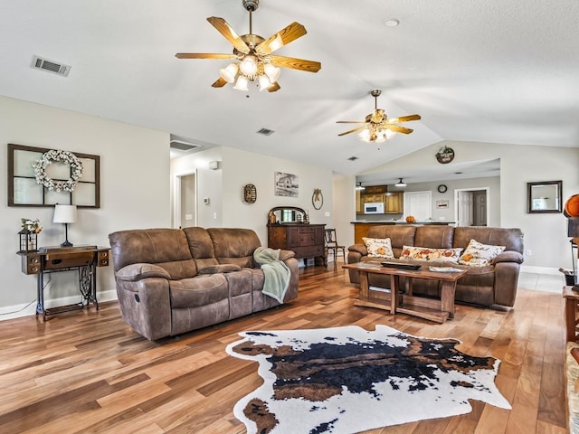 living room featuring ceiling fan, wood-type flooring, and vaulted ceiling