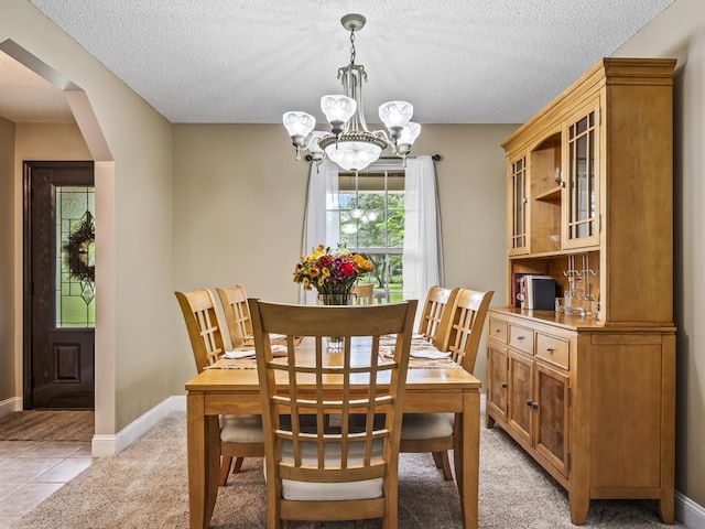 tiled dining space featuring an inviting chandelier and a textured ceiling