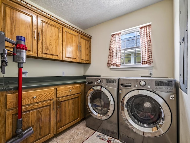 laundry room featuring washing machine and dryer, cabinets, a textured ceiling, and light tile patterned flooring