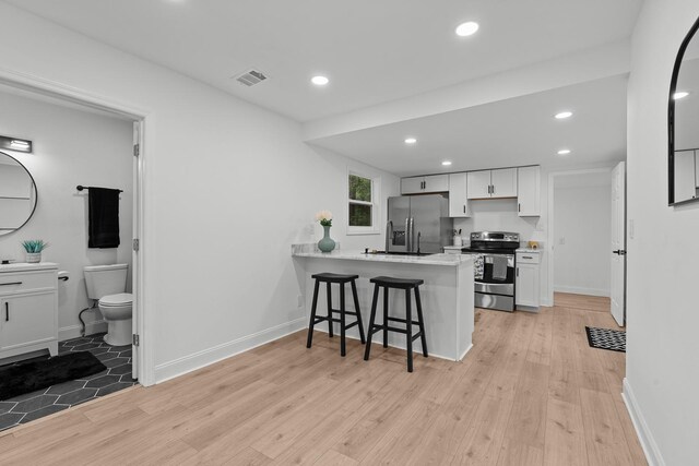 715 Caliark St, Tallahassee, FL 32304 - kitchen featuring appliances with stainless steel finishes, a breakfast bar, a peninsula, light wood-type flooring, and recessed lighting