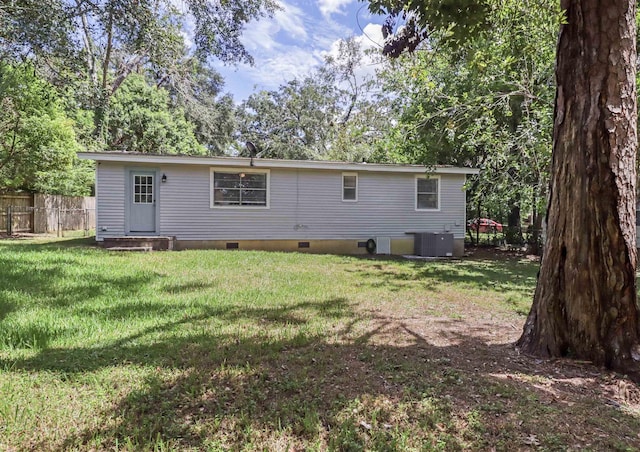 rear view of property with central AC unit and a yard