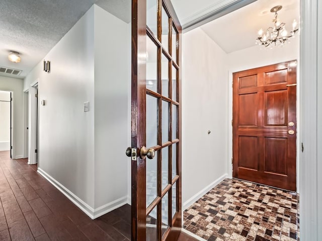 foyer featuring dark wood-type flooring, a notable chandelier, and a textured ceiling