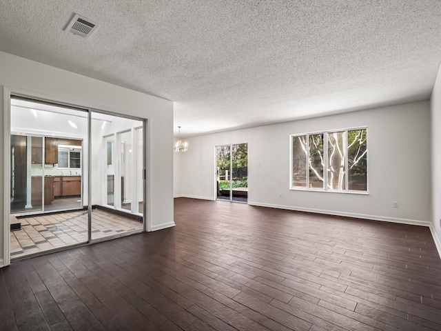 spare room with dark hardwood / wood-style flooring, a textured ceiling, and an inviting chandelier