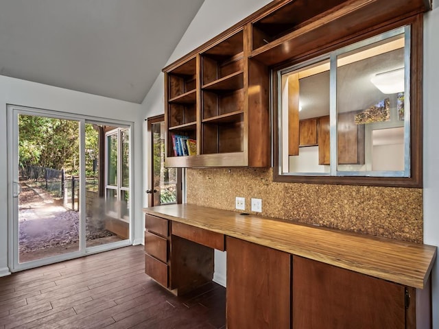 unfurnished office featuring lofted ceiling, dark hardwood / wood-style floors, and built in desk