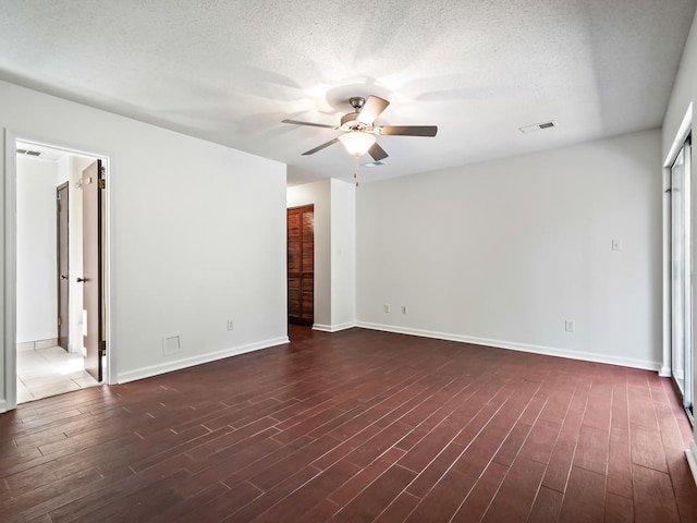 spare room featuring ceiling fan, dark wood-type flooring, and a textured ceiling