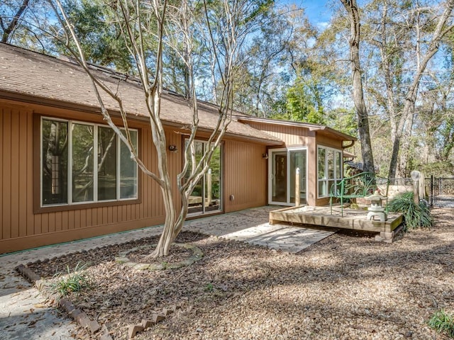 rear view of property featuring a sunroom and a deck