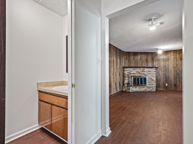 hallway featuring wooden walls, dark hardwood / wood-style flooring, and a textured ceiling