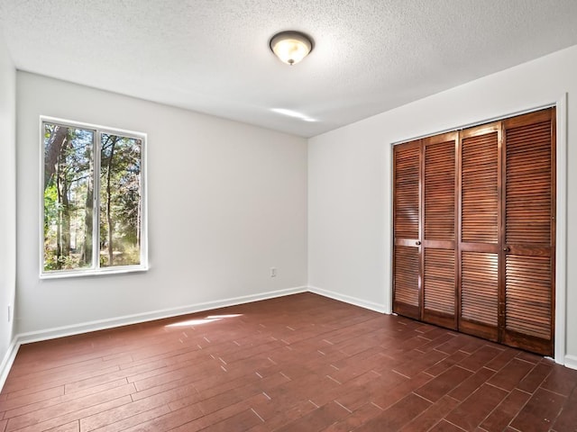 unfurnished bedroom with dark wood-type flooring, a closet, and a textured ceiling