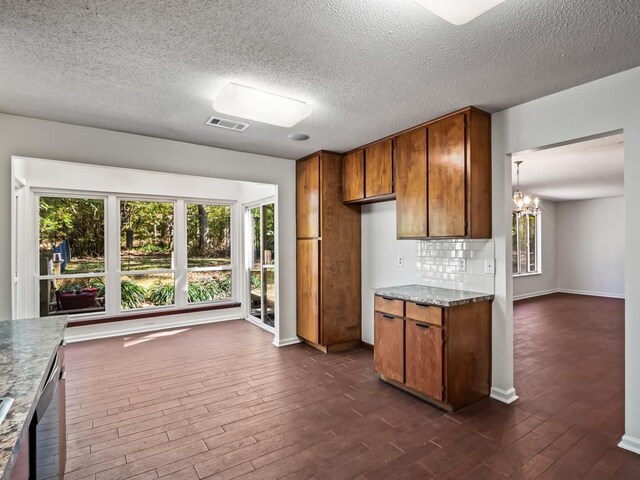 kitchen featuring dishwasher, stone counters, an inviting chandelier, backsplash, and dark hardwood / wood-style flooring