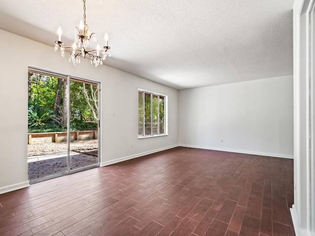 spare room with dark hardwood / wood-style floors, a chandelier, and a textured ceiling