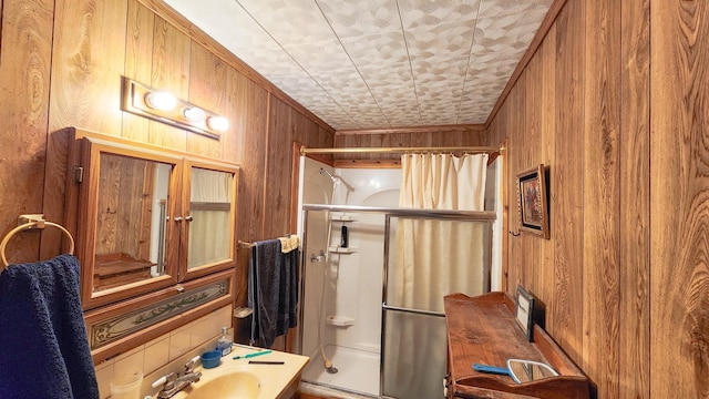 bathroom featuring a shower, sink, crown molding, and wood walls