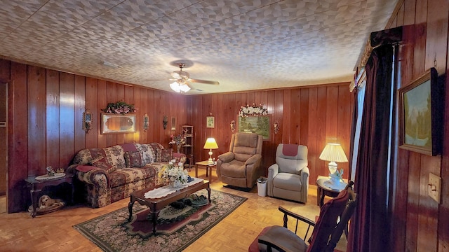 living room with ceiling fan, light parquet flooring, and wooden walls