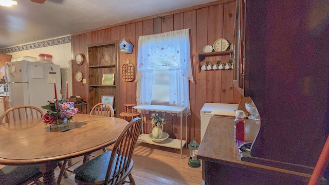 dining room with wooden walls and light hardwood / wood-style floors