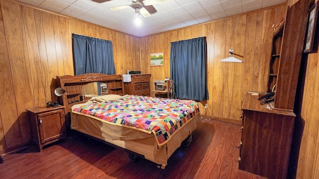 bedroom with dark wood-type flooring, ceiling fan, and wood walls