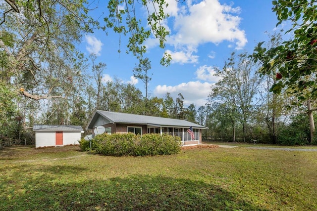 view of front facade featuring a front yard, a sunroom, and a shed