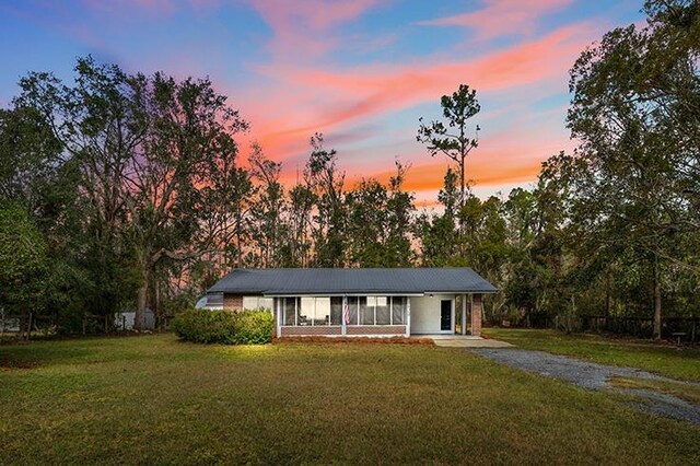 view of front of home with a front yard, a sunroom, and a carport