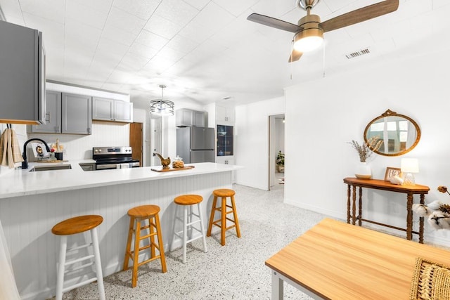 kitchen featuring kitchen peninsula, gray cabinets, stainless steel appliances, ceiling fan with notable chandelier, and sink