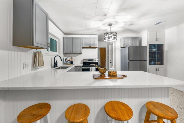 kitchen featuring a breakfast bar area, sink, gray cabinetry, and stainless steel appliances