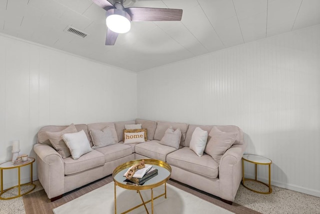 living room featuring ceiling fan and wood walls