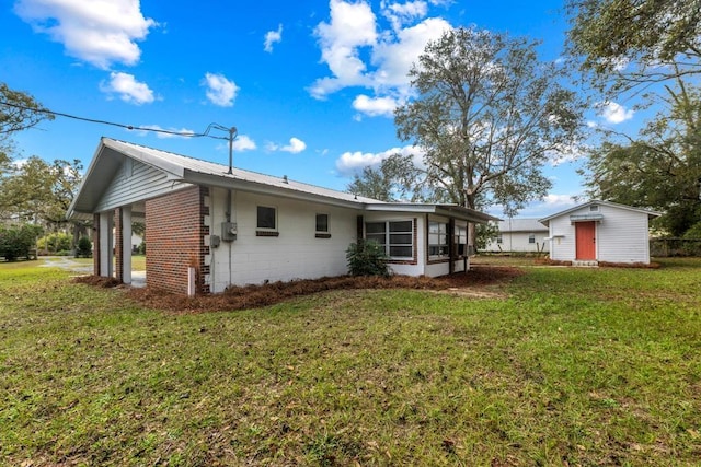 rear view of house featuring a lawn and a storage shed