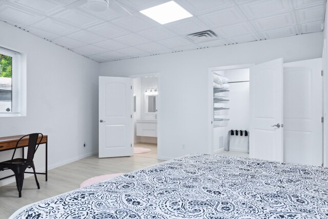 bedroom with light hardwood / wood-style floors and ensuite bath